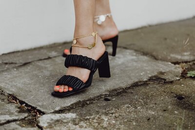 A flat lay of neutral-toned beauty and lifestyle items, including skincare bottles, a jar, a spray perfume, a knit cream sweater, and stacked books labeled “BOOK,” all set on a soft beige surface. The aesthetic is minimal, warm, and luxurious.