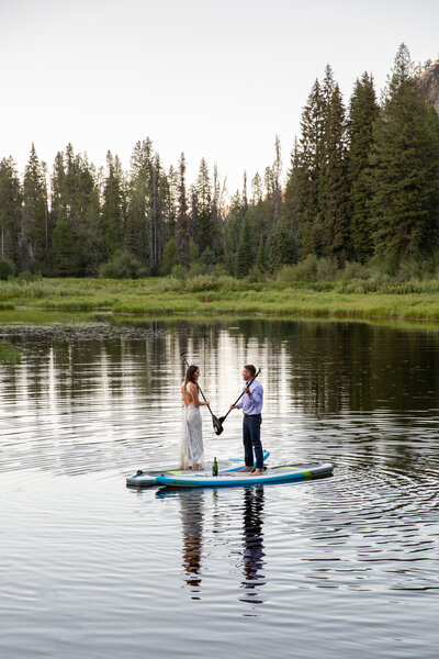 Bride & Groom paddle a canoe out on a lake in the fading light of a smokey  summer Montana evening.