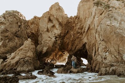 couple standing on rocks on the beach