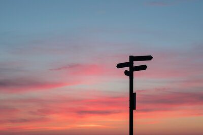 Sunset with directional signs pointing to directions