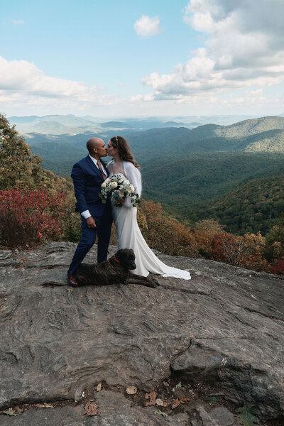 Couple shares a kiss with their dog sitting at their feet