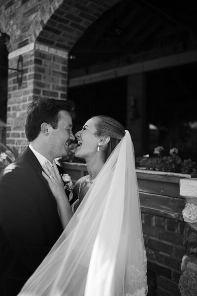 a joyful bride and groom smiling closely at each other in front of century room at grbic events wedding venue in st. louis