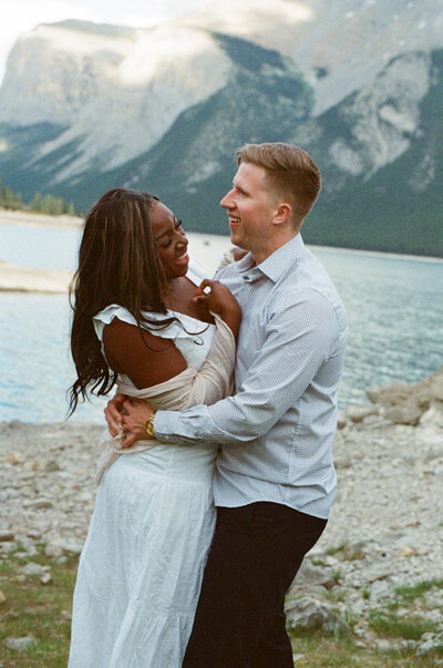 bride and groom laugh on the shores of an alpine lake in BC