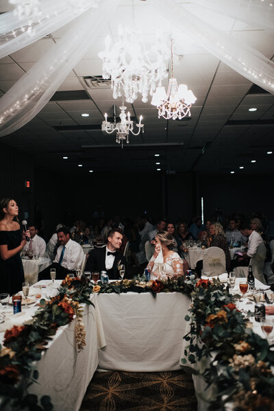 Western Kansas wedding reception in Colby Kansas where bride wipes away her tears as her husband looks at her during her sisters emotional speech at their wedding reception