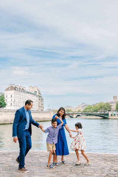 Playful family during a Paris family photoshoot on Île Saint-Louis in the city center, sharing joyful moments together.