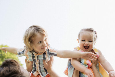 Joyful siblings playing outdoors, a lifestyle family moment captured by a Cleveland photographer.