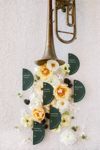 Unique detail shot of wedding seating chart with wedding flowers and vintage trumpet