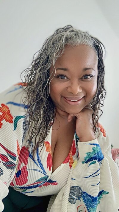 Letitia Hopkins smiling confidently in a business outfit, representing her work as a self-love and confidence coach helping women embody Main Character Energy and step fully into their power.