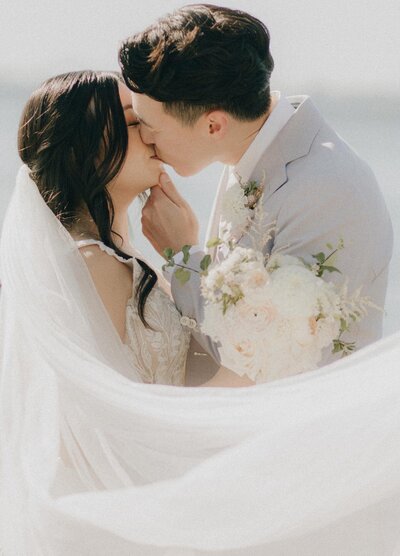 couple kissing with veil in the corner