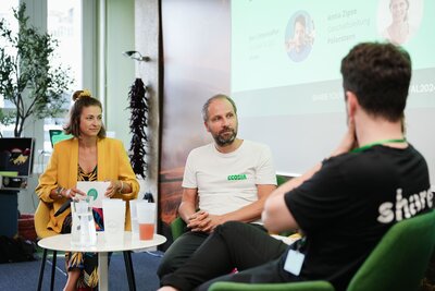 Moderatorin Hanna Zöller im gelben Blazer bei einer Paneldiskussion mit Expert:innen, Gesprächsrunde auf Bühne mit Publikum