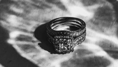 Black and white close-up of a diamond engagement ring set with patterned light and shadow.
