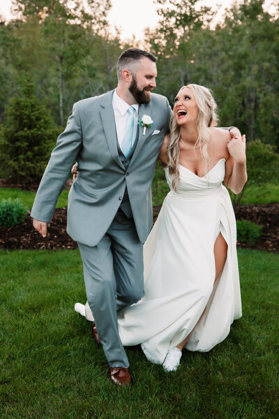 Newlyweds laugh while walking in a garden lawn at sunset with arms around each other for Milwaukee Wedding Photographer