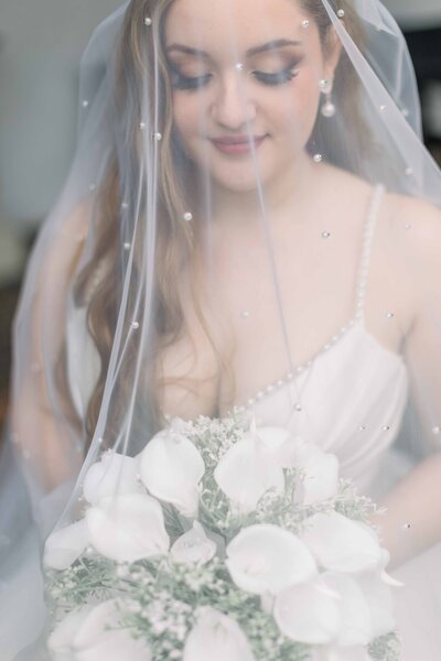 Bridal bouquets being held by a bride and bridesmaids - white, ivory, dusty green