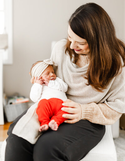 New mom holds her newborn and looks down on her during newborn session in Londonderry, New Hampshire