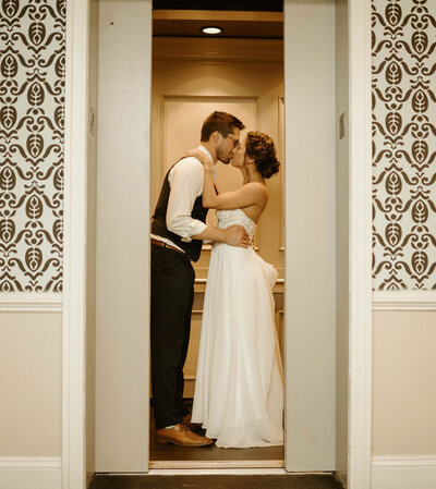 groom and bride kissing as elevator doors close
