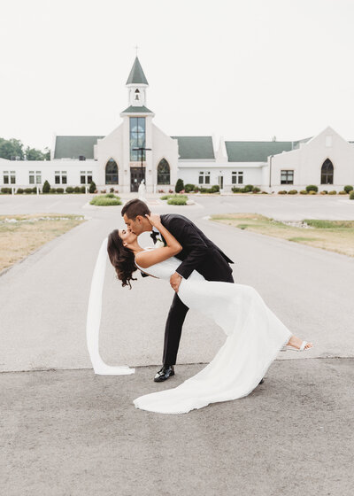 bride and groom kissing in front of church
