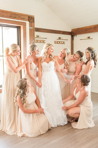 bride surrounded by bridesmaids on wedding day wearing champagne bridemsids dresses