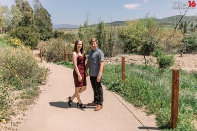 Engaged couple stop while walking on a dirt walking trail for a photo opportunity