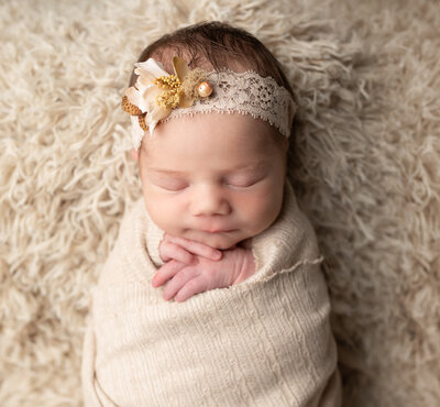newborn baby girl wrapped in beige swaddle for newborn studio portraits