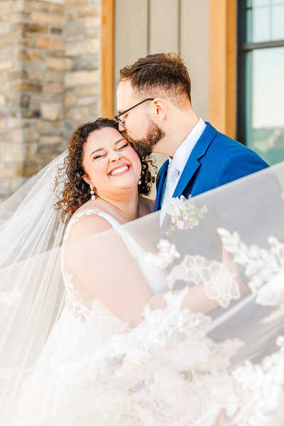 happy bride and groom posing for the camera in a stunning veil shot