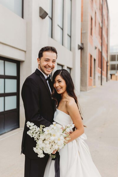 bride and groom smiling outside of Outreach Event Space in the downtown Crossroads area of Kansas City