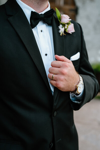 Groom's hand on jacket with wedding ring