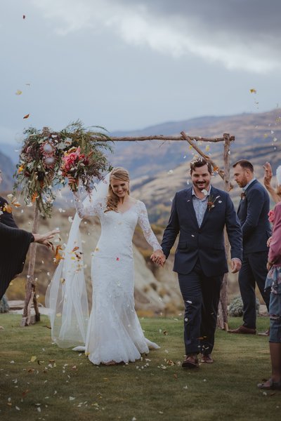 Bride and groom celebrating while petals are thrown over them