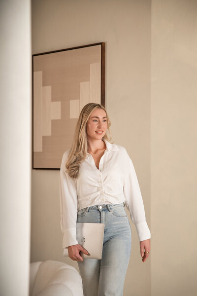 Brandingfoto in Studio Laurant: lachende vrouw met laptop in de hand, geposeerd bij de elegante bogen voor een professionele en stijlvolle uitstraling.