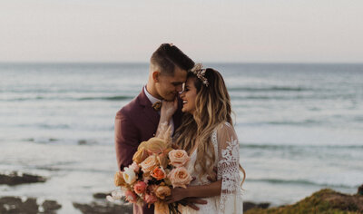 A couple kisses next to the ocean during their California elopement