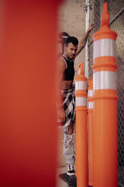 person hangs off chainlink fence with cones along street personal branding session Denver