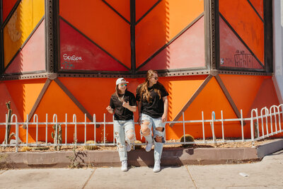 Two friends sitting against a railing.