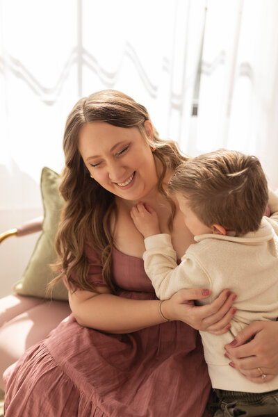 Mother with toddler son tickling her neck while she laughs
