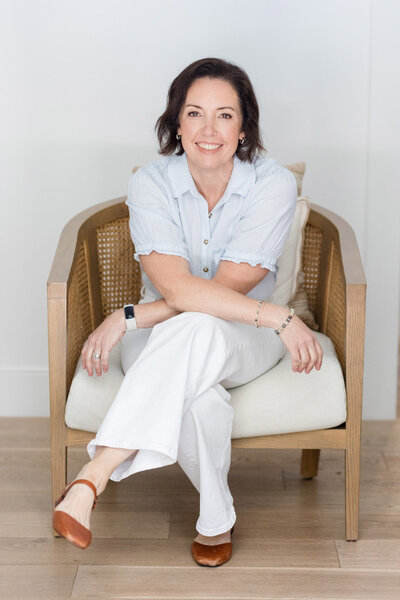 Coach Dinah McBride sitting in a chair with her legs crossed, smiling