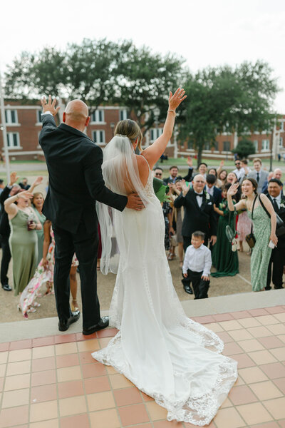 bride and groom waving to guests at send off