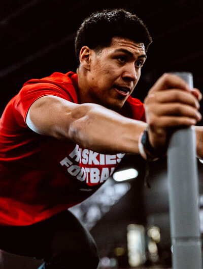 An NFL hopeful pushes a sled during his workout in the gym.