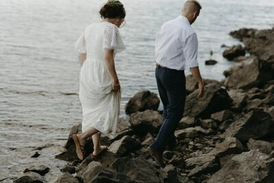 bride and groom wander along the lakeshore