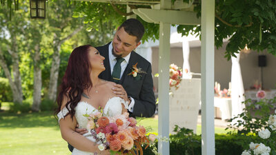 bride and groom smiling at each other while bride holds bridal bouquet