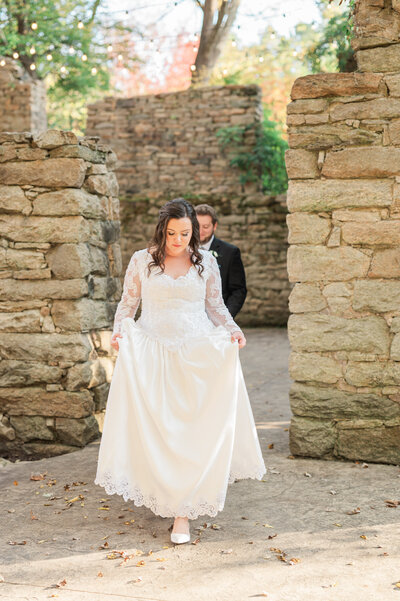 A wedding couple walking through a stone walls