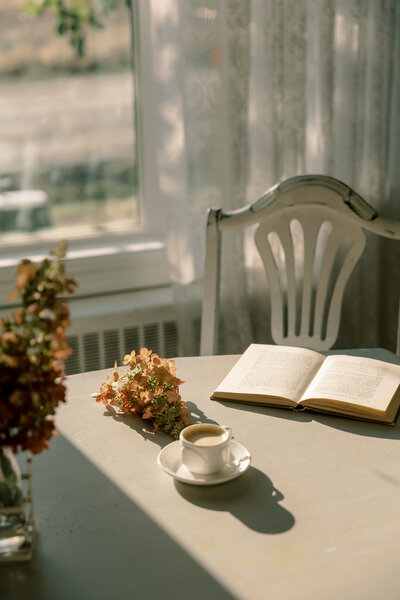 A table with flowers, a cup of coffee and beams of sunlight 