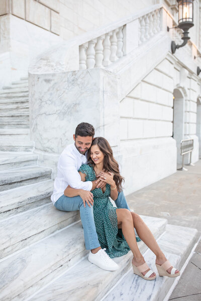 Engaged couple sitting and smiling in portrait on museum steps