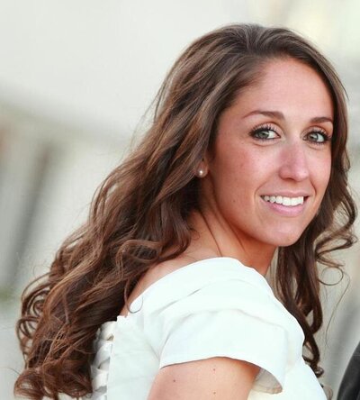 A bride wearing a white dress smiles with curls in her hair
