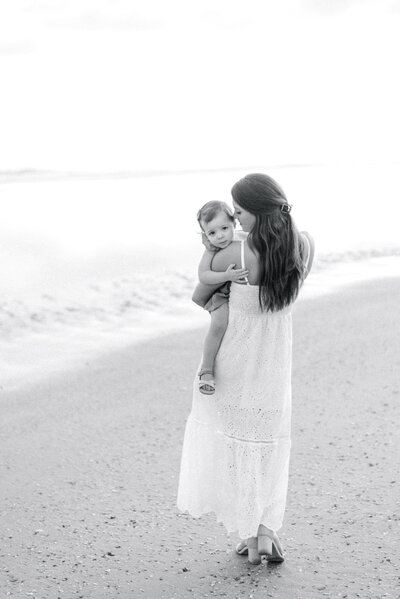 Mother holding her daughter and baby looking backwards over her shoulder on Isle of Palms beach in South Carolina
