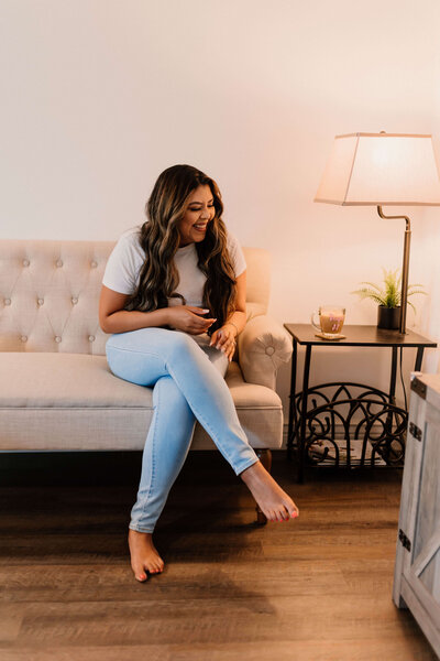 Celeste Gonzalez smiling and sitting on a couch with a coffee on a table beside her