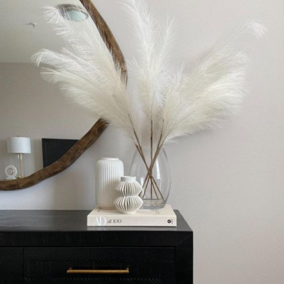 decorated simple modern console with pampas grass, a book and vases