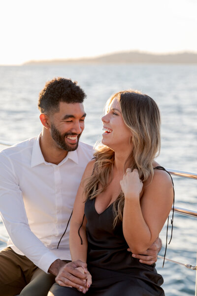 engaged couple laughing on a sailboat in california