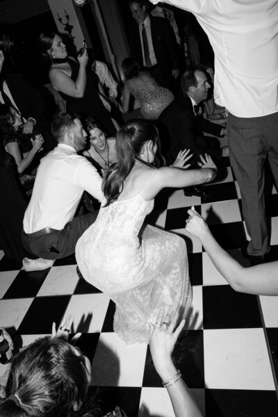 Bride dancing joyfully on a black and white checkered dance floor at The Madison Club, surrounded by elegant decor.