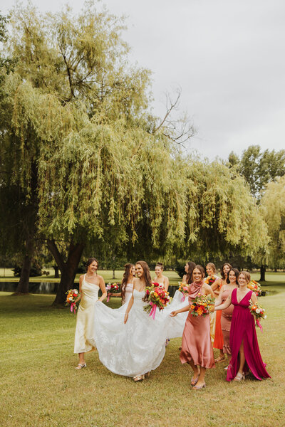 Bride walking and laughing with her bridal party during joyful wedding portraits.