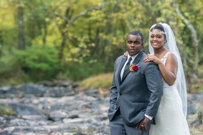 a Black wedding couple pose in front of a river