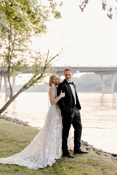 bride and groom embracing by river