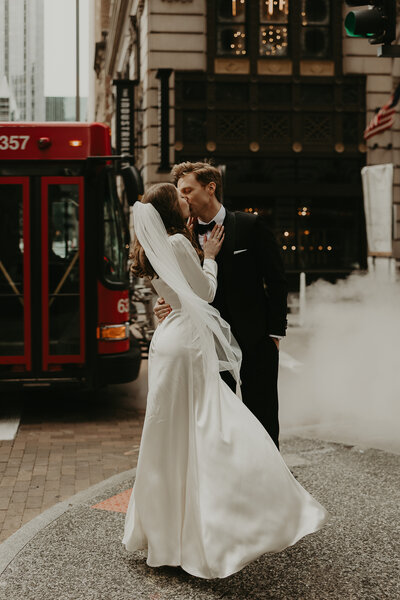 bride and groom kissing front of bus